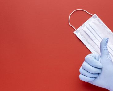 vista-superior-mano-dando-pulgares-arriba-mascara-medica-espacio-copia_23-2148781236